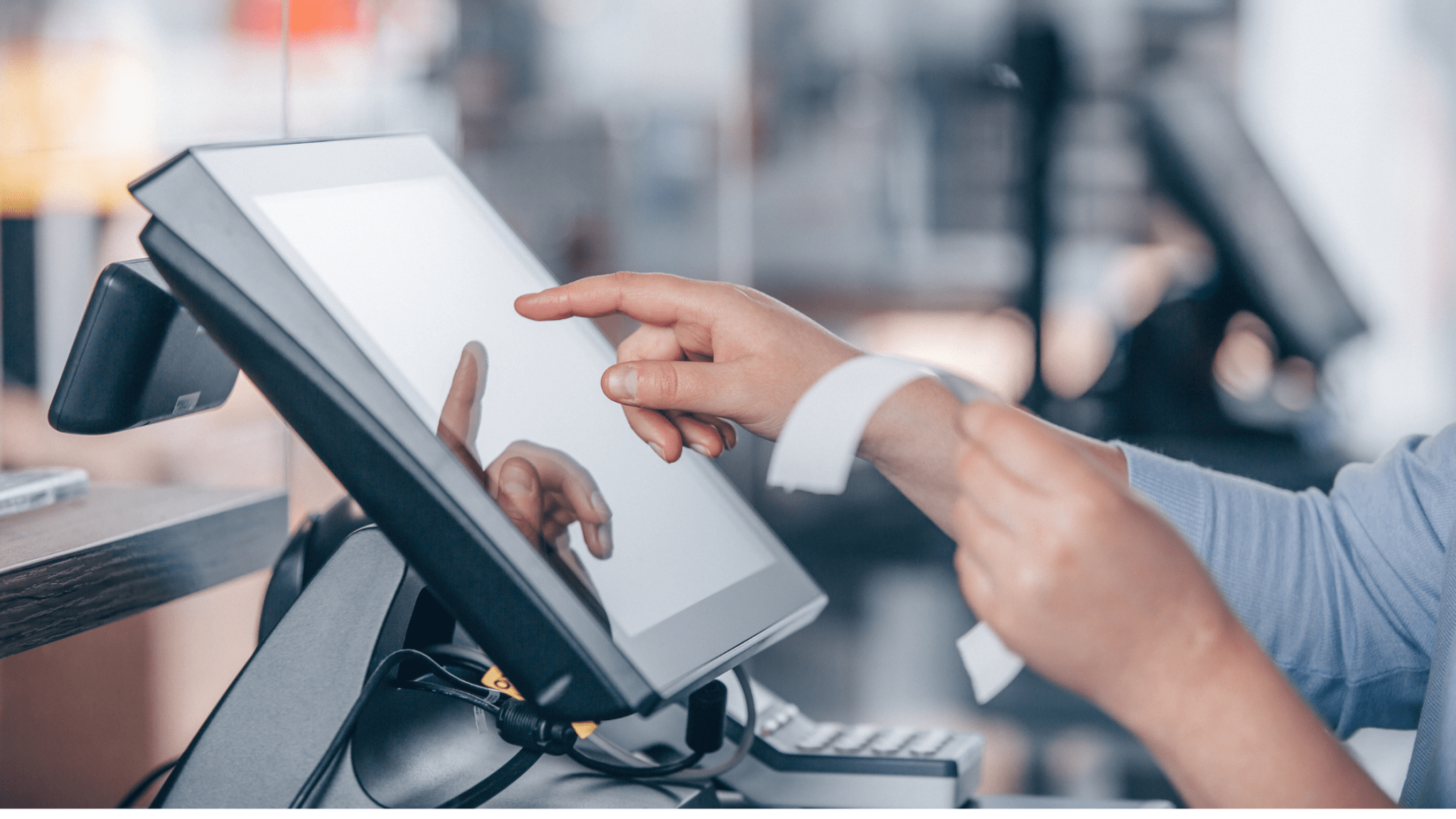 Close-up of a person using a touchscreen POS system, holding a receipt in one hand while the other touches the screen